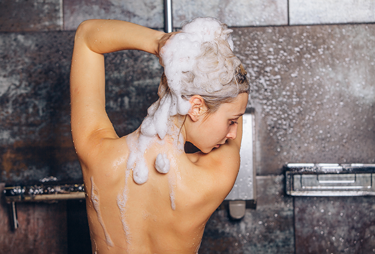 Woman in a shower with Shampoo in hair
